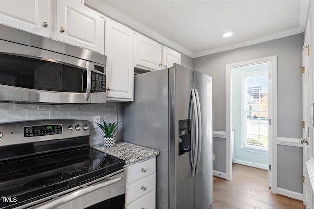 kitchen featuring crown molding, light wood-type flooring, appliances with stainless steel finishes, decorative backsplash, and white cabinets