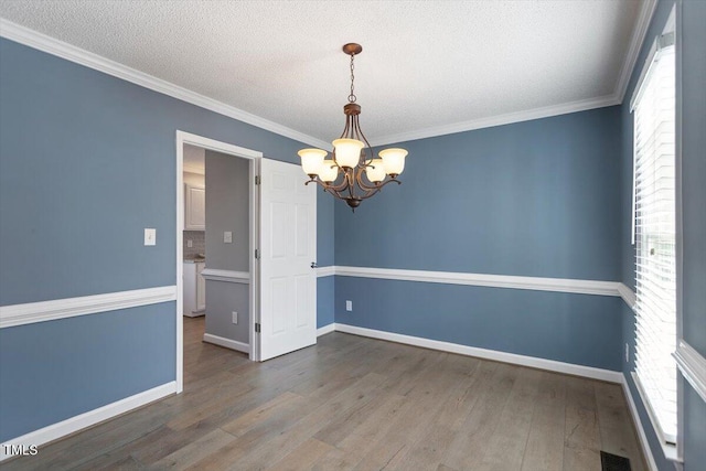 empty room with a notable chandelier, hardwood / wood-style flooring, and a healthy amount of sunlight