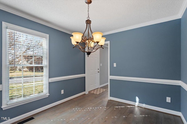 spare room with crown molding, dark wood-type flooring, a textured ceiling, and a chandelier