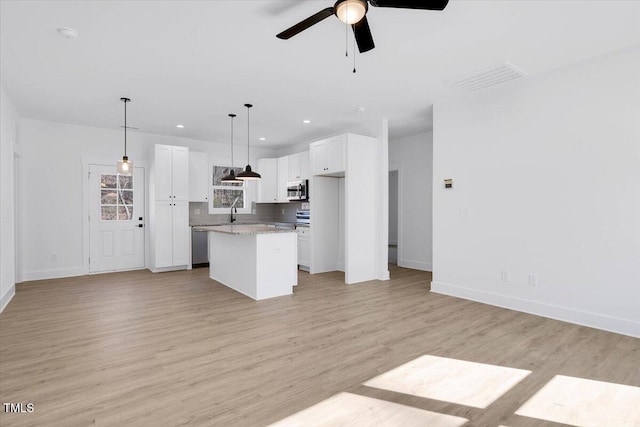 kitchen with white cabinetry, decorative light fixtures, light hardwood / wood-style floors, and a kitchen island