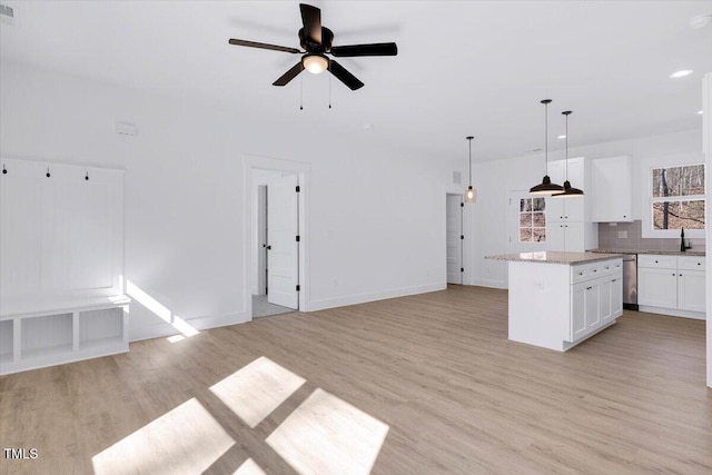 kitchen with pendant lighting, tasteful backsplash, white cabinetry, a center island, and light hardwood / wood-style flooring