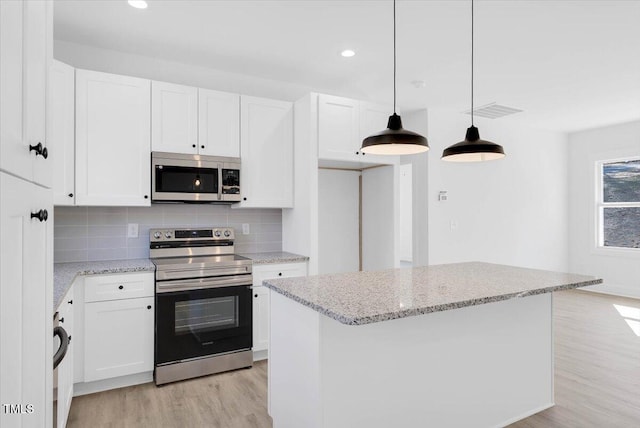 kitchen featuring white cabinetry, appliances with stainless steel finishes, decorative light fixtures, and light stone countertops