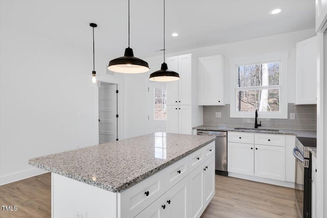 kitchen with a kitchen island, appliances with stainless steel finishes, pendant lighting, white cabinetry, and sink