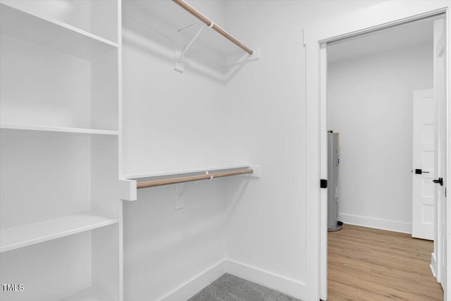 walk in closet with light hardwood / wood-style floors and water heater