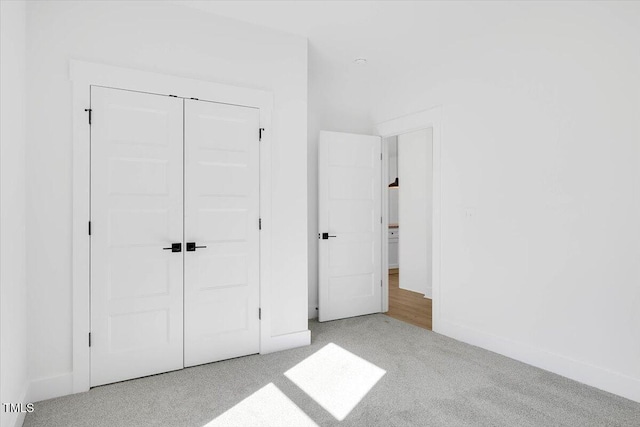 unfurnished bedroom with light colored carpet and a closet