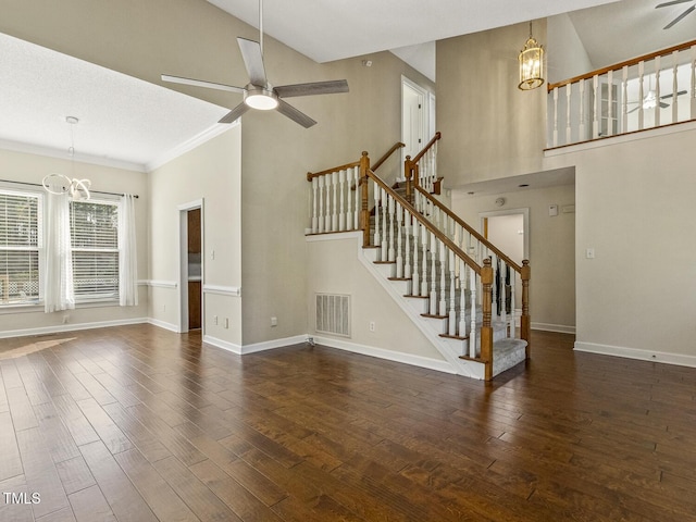 unfurnished living room with a high ceiling, dark hardwood / wood-style floors, and ceiling fan with notable chandelier