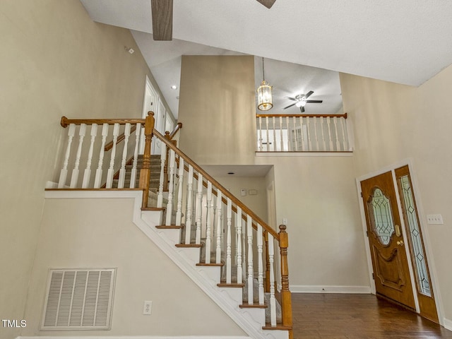 stairs with a high ceiling, hardwood / wood-style floors, and ceiling fan