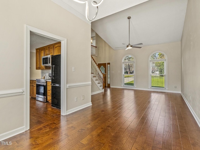 unfurnished living room with high vaulted ceiling, dark hardwood / wood-style floors, and ceiling fan