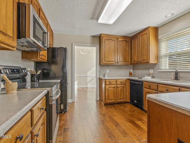 kitchen with sink, hardwood / wood-style floors, decorative backsplash, and black appliances