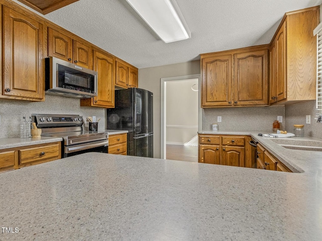 kitchen featuring stainless steel appliances, sink, a textured ceiling, and backsplash