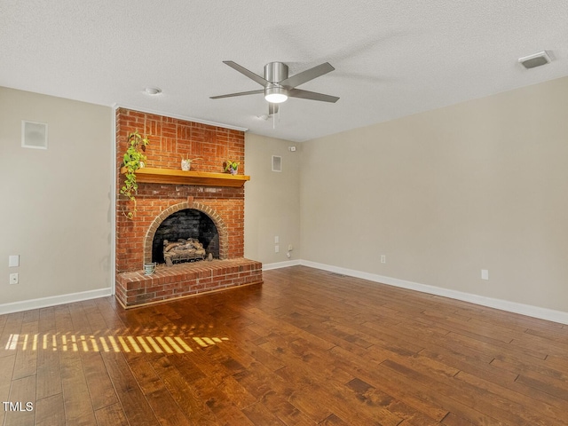 unfurnished living room with ceiling fan, hardwood / wood-style floors, a brick fireplace, and a textured ceiling