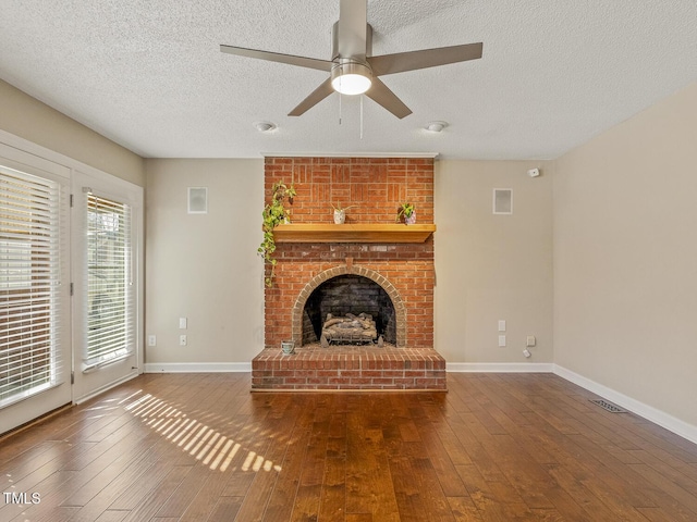 unfurnished living room featuring dark hardwood / wood-style flooring, a brick fireplace, a textured ceiling, and ceiling fan