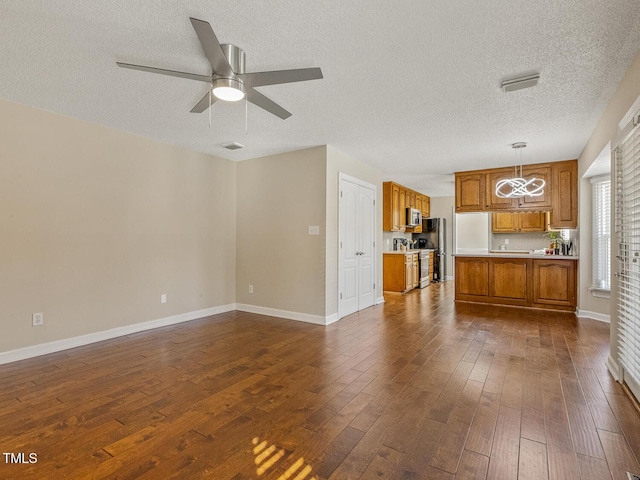 unfurnished living room with a textured ceiling, dark hardwood / wood-style floors, and ceiling fan