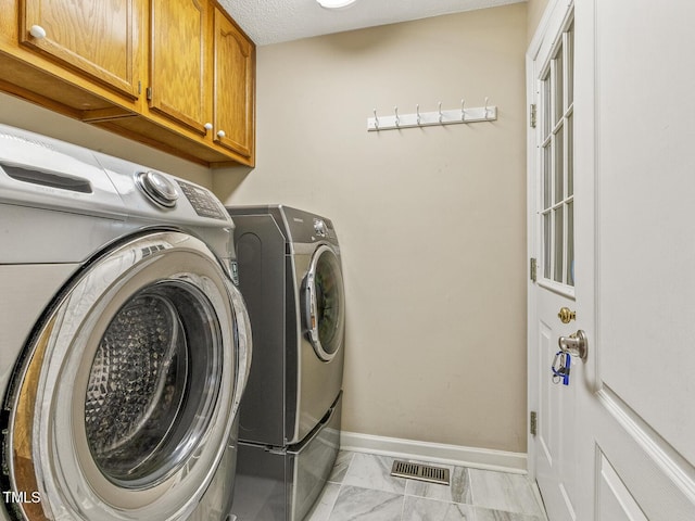 clothes washing area with cabinets and washer and dryer