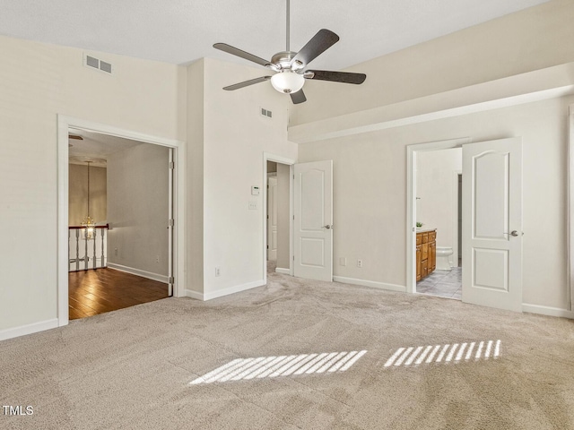 unfurnished bedroom with ensuite bathroom, carpet flooring, and high vaulted ceiling