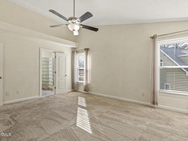 carpeted empty room with ceiling fan, lofted ceiling, and a textured ceiling