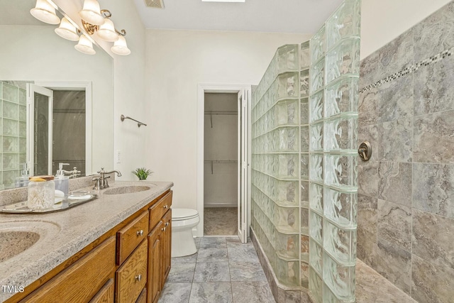 bathroom featuring vanity, toilet, and a tile shower