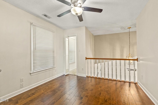 empty room with ceiling fan, a textured ceiling, and dark hardwood / wood-style flooring