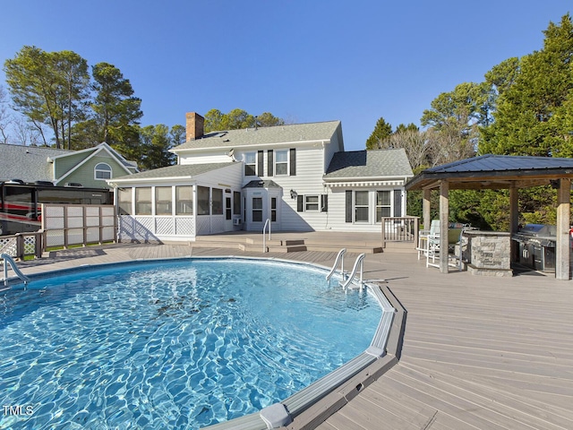 view of pool featuring a gazebo, a sunroom, a grill, and a deck