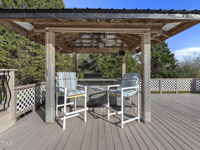 wooden deck featuring ceiling fan and exterior bar