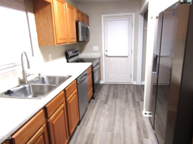 kitchen with stainless steel appliances, sink, and light wood-type flooring