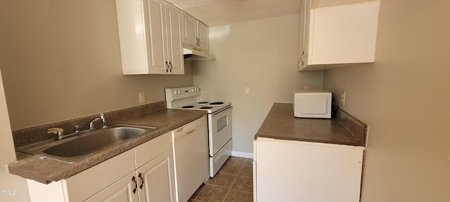 kitchen with sink, a textured ceiling, dark tile patterned floors, white appliances, and white cabinets