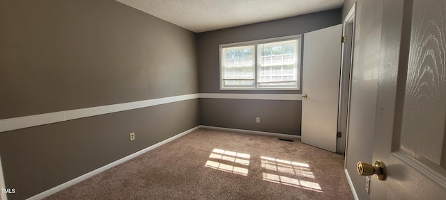 carpeted spare room featuring a textured ceiling