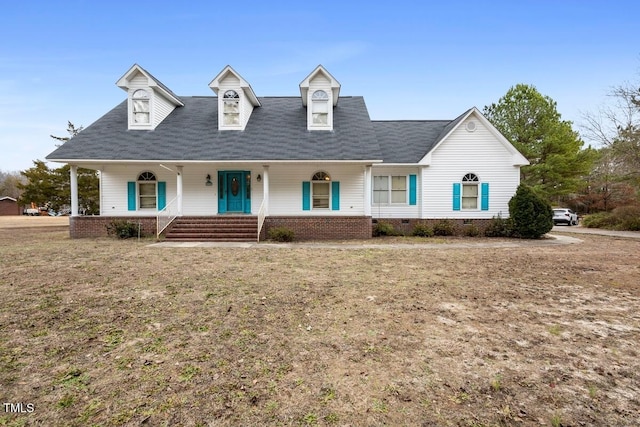 cape cod-style house featuring a front lawn and covered porch