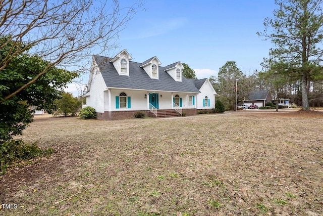 cape cod home featuring a porch and a front yard