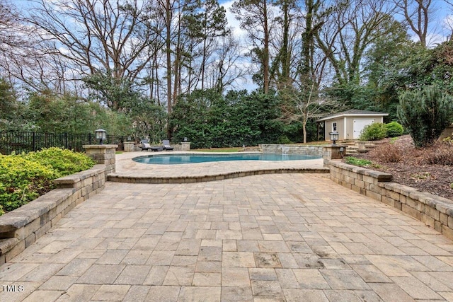 view of swimming pool with fence, an outbuilding, a fenced in pool, and a patio