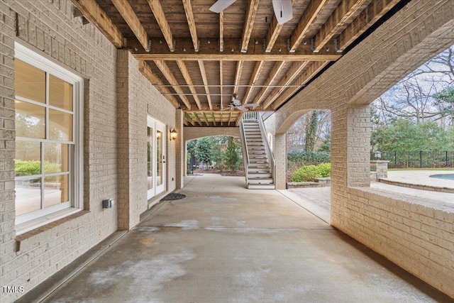 view of patio with a ceiling fan, french doors, fence, and stairway