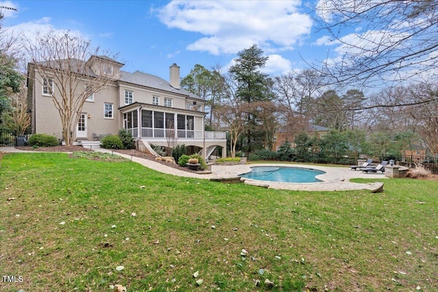 back of house with a yard, a chimney, a sunroom, a patio area, and fence