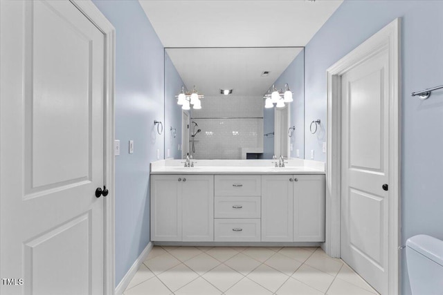 bathroom with baseboards, double vanity, a sink, and tile patterned floors