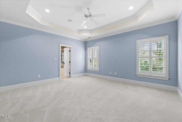 spare room with ornamental molding, a tray ceiling, baseboards, and carpet