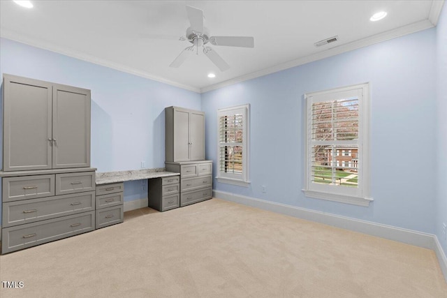 unfurnished bedroom featuring built in desk, light colored carpet, visible vents, ornamental molding, and baseboards