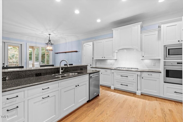 kitchen featuring crown molding, appliances with stainless steel finishes, white cabinets, and a sink