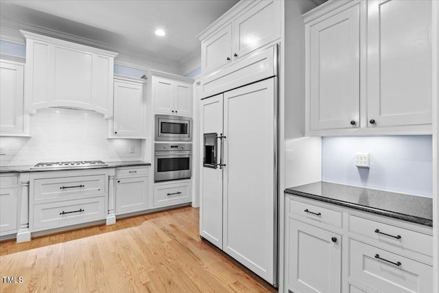 kitchen with crown molding, tasteful backsplash, light wood-style floors, white cabinetry, and built in appliances