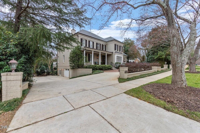 view of front of home with a garage, driveway, a chimney, and a balcony