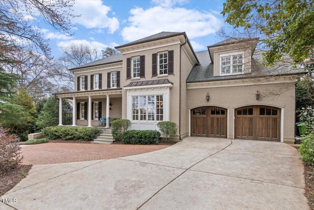 view of front of house featuring covered porch, brick siding, an attached garage, and concrete driveway