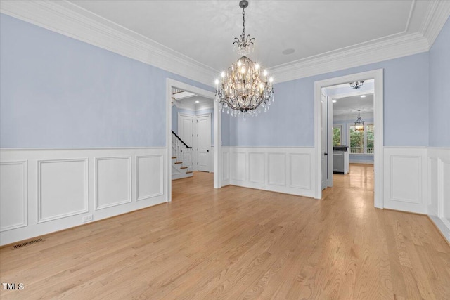 unfurnished dining area with light wood finished floors, visible vents, stairway, an inviting chandelier, and wainscoting