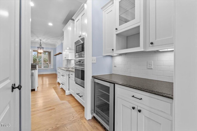 kitchen featuring white cabinets, decorative backsplash, wine cooler, appliances with stainless steel finishes, and light wood-style floors