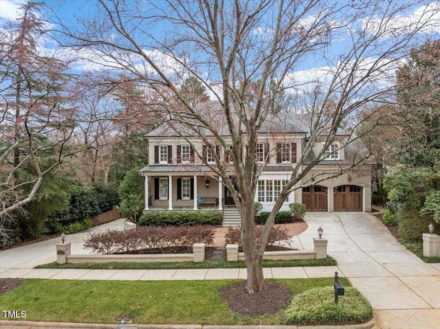 view of front of house with driveway, an attached garage, and a porch