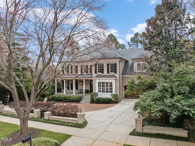 view of front of home with a porch, concrete driveway, and roof with shingles