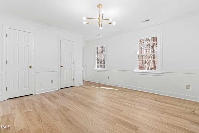 unfurnished bedroom featuring ornamental molding, a notable chandelier, and light hardwood / wood-style flooring