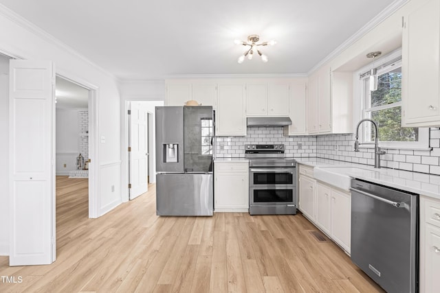 kitchen featuring sink, appliances with stainless steel finishes, backsplash, ornamental molding, and white cabinets