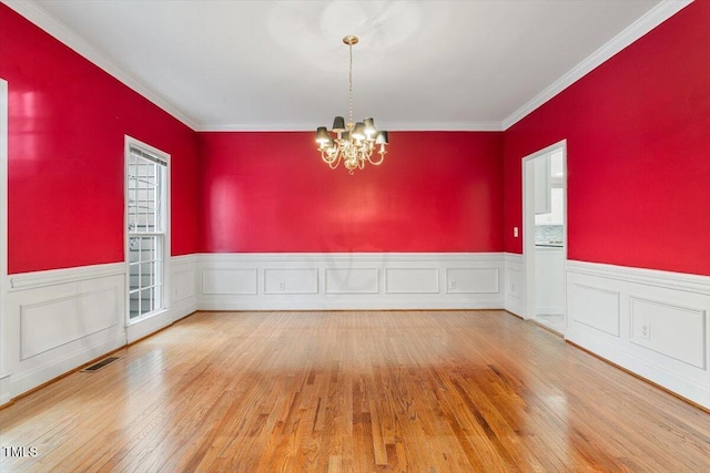 unfurnished room featuring wood-type flooring, ornamental molding, and a notable chandelier