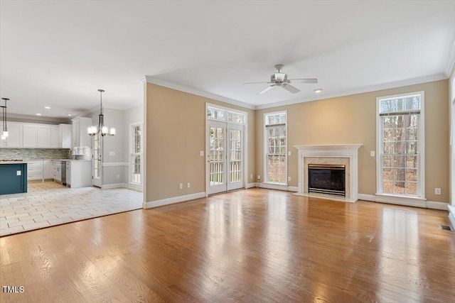 unfurnished living room with crown molding, ceiling fan with notable chandelier, and light wood-type flooring