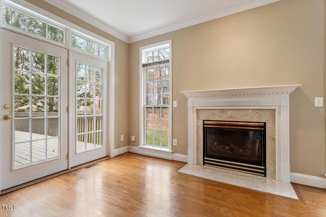 unfurnished living room featuring crown molding, light wood-type flooring, and a fireplace