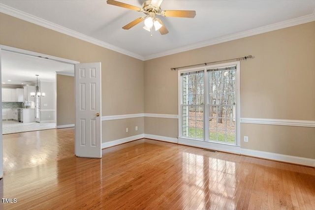 spare room with ceiling fan with notable chandelier, a healthy amount of sunlight, crown molding, and light hardwood / wood-style floors