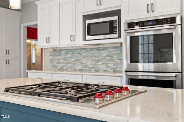 kitchen with backsplash, stainless steel appliances, white cabinets, and blue cabinets